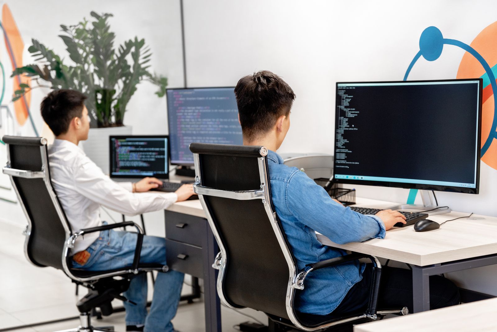 Developers working side by side on software at a desktop workstation